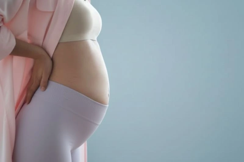 Gravid kvinde i andet trimester holder kærligt om sin mave